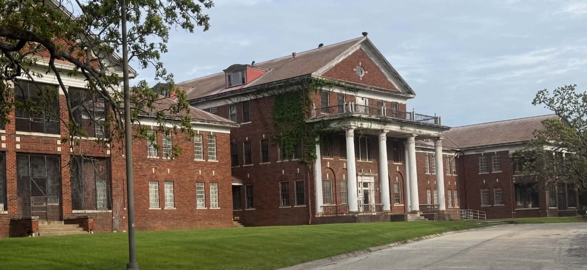 A large historic brick building with a columned entrance prior to demolition in Kansas